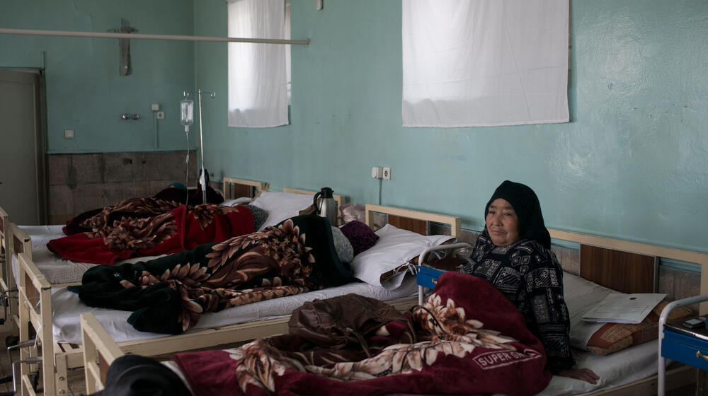 An elderly fistula survivor rearranges herself in her bed at a health care center.