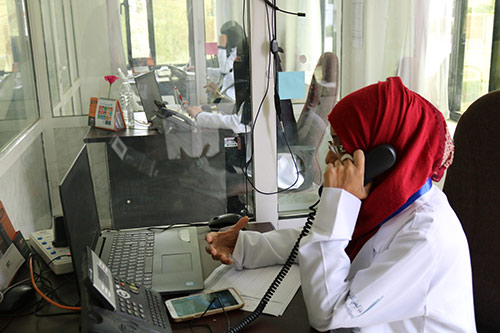A woman in a red hijab takes a phone call at a UNFPA-supported mental health care hotline. 