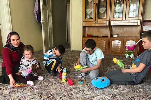 Salimeh and her four children sit on the carpet of their new home, playing with toys.