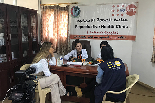 Dashni Murad sits with UNFPA staff in a reproductive health clinic. They are being filmed as they interact. 