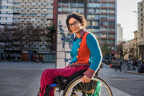 A woman in a wheelchair smiles at the camera.