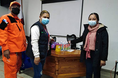 Individuals wearing face masks prepare kits with essential supplies.