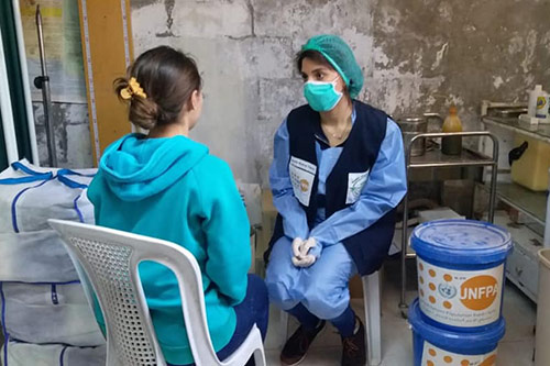 تاة مراهقة تتحدث إلى أحد العاملين في فريق طبي متنقل في سوريا