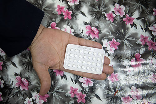 A woman's hand holds a pack of oral contraceptive pills. 