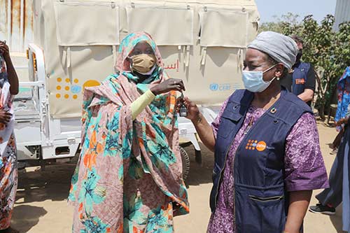 Dr. Kanem hands keys to the ambulance to a local woman community leader. Both women are wearing face masks.