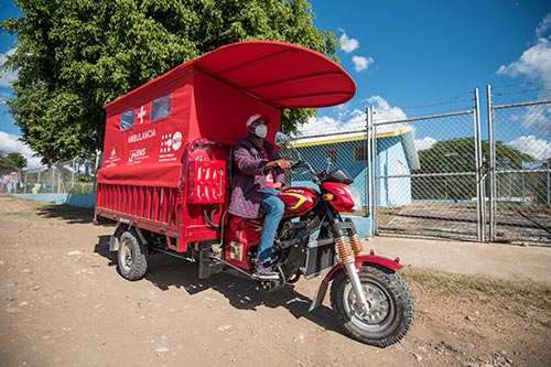 A red motorcycle ambulance stands ready to deliver women to care. 