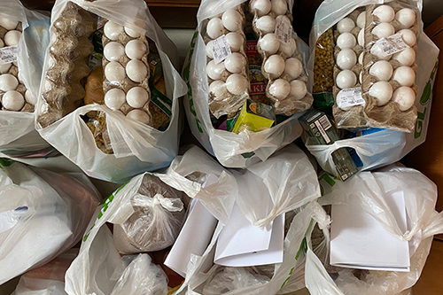 Plastic bags are filled with food items including egg cartons and various other groceries.
