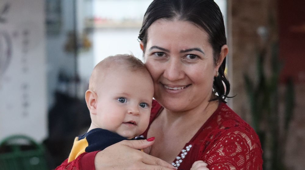 Une femme sourit, tenant un bébé dans les brase, au Paraguay. © UNFPA Paraguay/Edson Riveiro