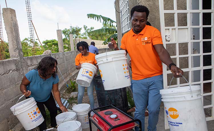 Three aid workers organise buckets with UNFPA logos
