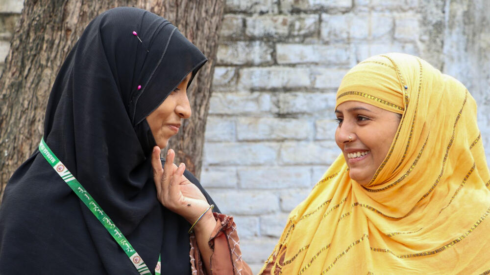  Une mère tend la main vers sa fille, toutes les deux souriant