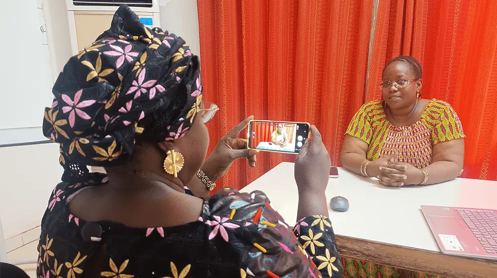 A woman films another woman with a mobile phone.