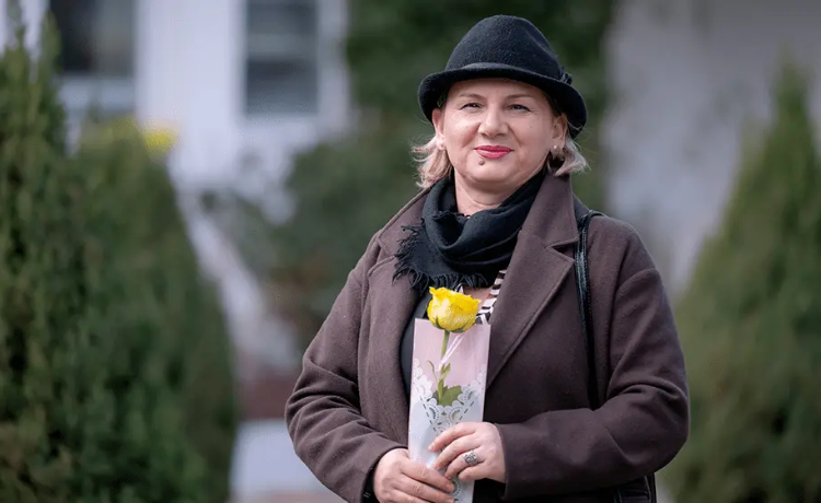 A woman holds a yellow rose.