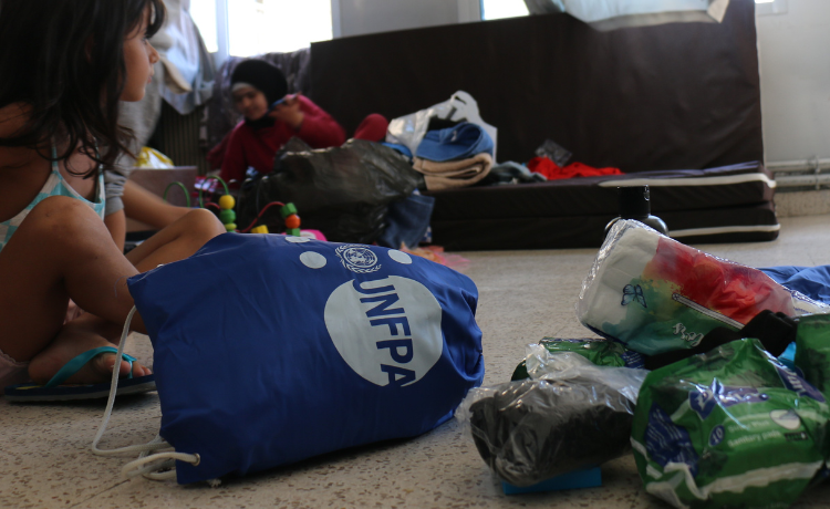 A blue bag with a white UNFPA logo is turned on its side, beside a small pile of menstrual pads and other hygiene items