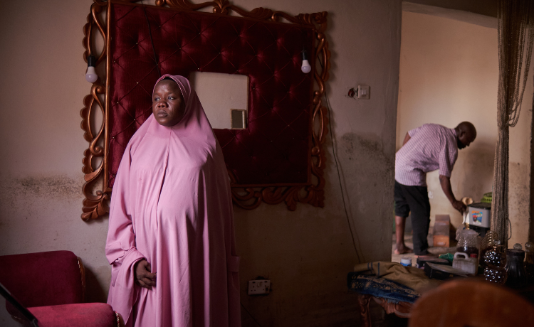 Una mujer con hiyab rosa contempla su casa dañada por las inundaciones