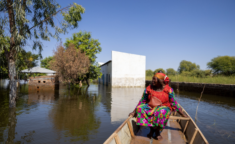 Une femme est assise dans un canoë et regarde des bâtiments immergés dans l’eau