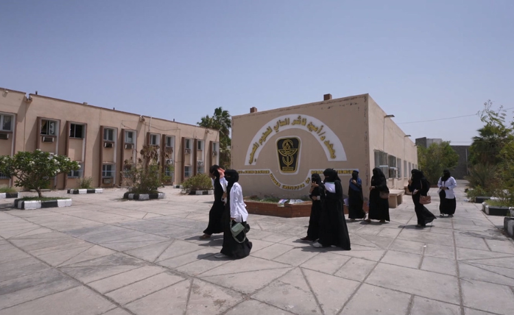 A group of women cross a courtyard in front of a higher education building