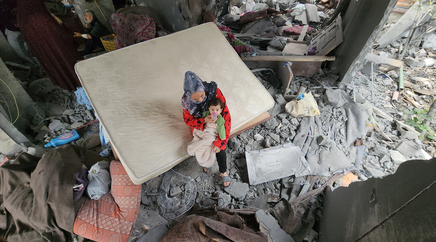 A mother feeds her newborn amid the rubble of their bombed home in Khan Younis.