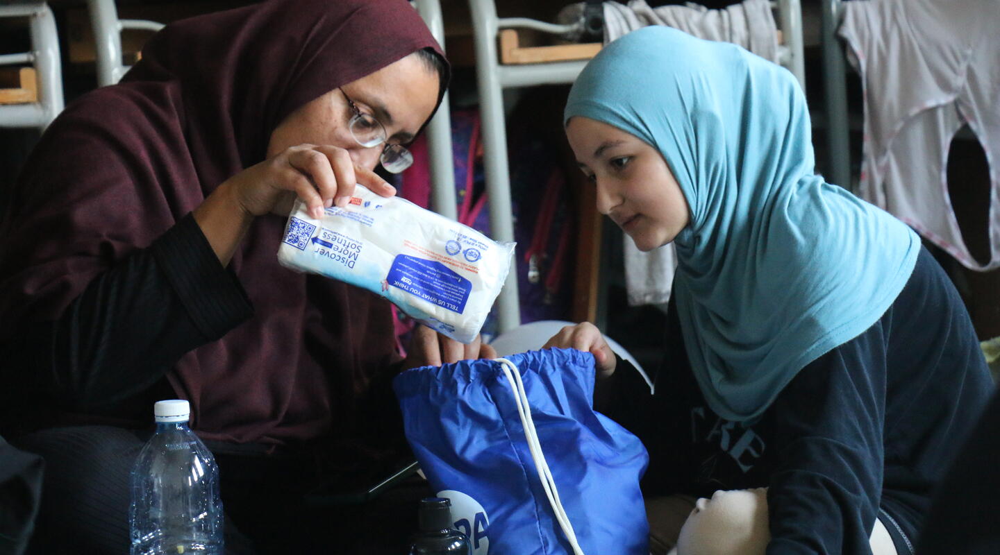 A mother and daughter receive hygiene kits at a school serving as a shelter in Lebanon.