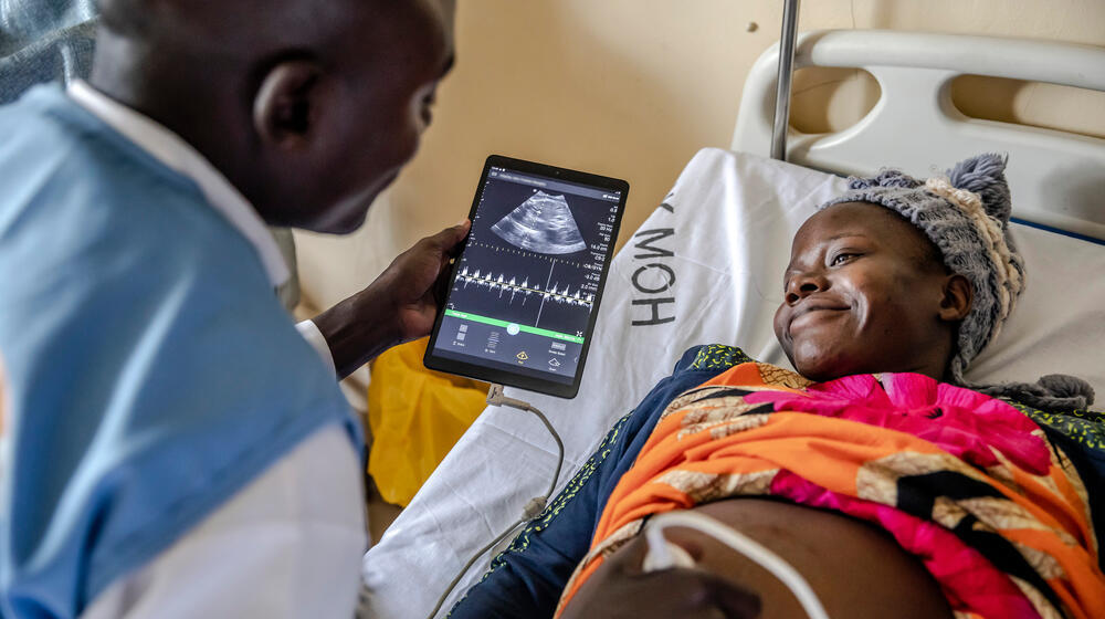 A midwife examines a woman using a portable ultrasound device.