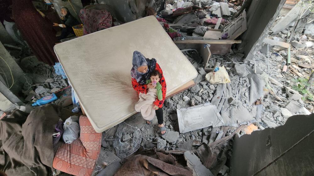 A mother with her newborn on the rubble of their bombed home in Khan Younis.