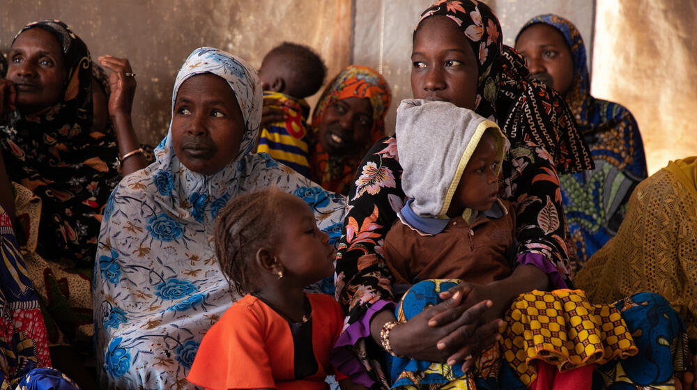Women and children in Mali sitting together listening to a midwife raising awareness on the prevention of mother-to-child transmission of HIV.