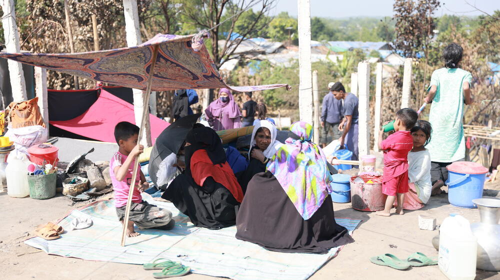مجموعة من لاجئي الروهينجا الذين أصبحوا بلا مأوى مرة أخرى بعد اندلاع حريق في مخيمهم يجلسون على سجادة على الأرض.