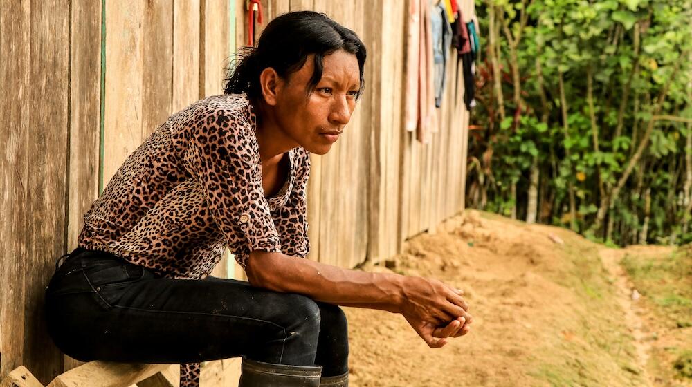 امرأة عابرة تعيش وتعمل في منطقة الأمازون في بيرو، تجلس خارج مبنى.