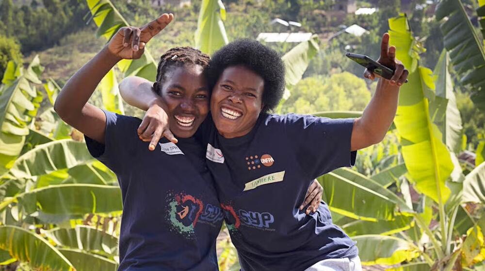 Two young women hold their arms up in cheering gesture.