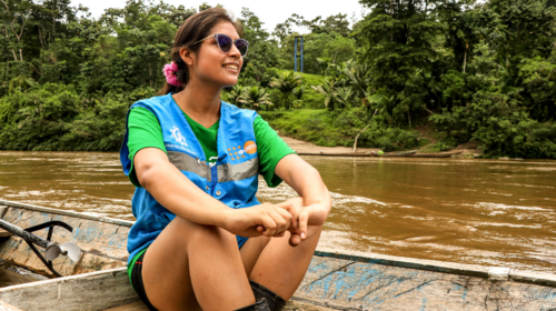 Una joven sentada en un bote de remos en un río en medio de la selva.